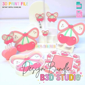 May include: A selection of pink and white 3D-printed cherry and bow designs. The designs include a badge reel, hair clips, a heart-shaped tray, and a picture frame. Text includes "3D PRINT FILE" and "Design Bundle B3D STUDIO".