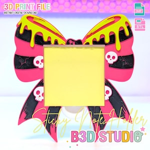 May include: A pink and black bow-shaped sticky note holder with yellow dripping accents and skull details. The holder has a yellow square for notes and the text "Sticky Note Holder" and "B3D STUDIO". The image also includes the text "3D PRINT FILE".