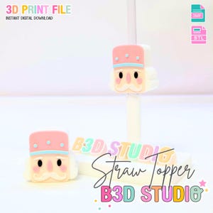 May include: A 3D-printed straw topper featuring a cartoon nutcracker design. The topper has a pink hat with blue trim and a white face with a mustache. The image includes the text "3D PRINT FILE" and "STRAW TOPPER".