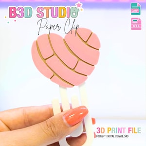 May include: A pink heart-shaped paper clip with a light brown grid pattern, held by a white clip. The text "B3D STUDIO Paper Clip" is at the top, and "3D PRINT FILE" is at the bottom. The clip is a digital download.