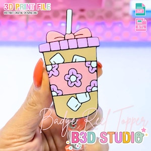 May include: A cartoon-style badge reel topper in the shape of a coffee drink. The design features a pink floral pattern, ice cubes, and a bow. Text on the image includes "3D PRINT FILE" and "INSTANT DIGITAL DOWNLOAD". The bottom of the image has the text "B3D STUDIO".