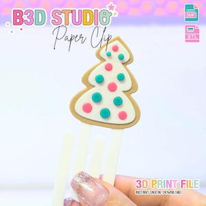 May include: A paper clip with a Christmas tree design. The tree is white with pink and teal dots, outlined in brown, and attached to a white clip. The image includes the text "B3D STUDIO Paper Clip" and "3D PRINT FILE INSTANT DIGITAL DOWNLOAD".