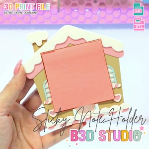 Puede incluir: Un soporte para notas adhesivas con forma de casa de jengibre con una nota adhesiva rosa. El soporte es de color beige, blanco y rosa, con el texto "Sticky Note Holder" y "B3D STUDIO". La imagen también incluye el texto "3D PRINT FILE" y "INSTANT DIGITAL DOWNLOAD".
