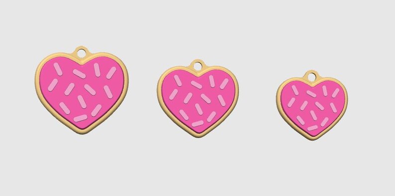 May include: Three heart-shaped charms with a pink frosted design and sprinkles. The charms have a gold-colored border and a small hole at the top for hanging. The sizes vary, with the largest charm on the left and the smallest on the right.