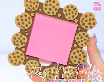 Puede incluir: Un soporte cuadrado marrón para notas adhesivas con diseño de galletas. El soporte tiene un bloc de notas adhesivas rosa en el centro y está rodeado de galletas con chispas de chocolate. El texto "3D PRINT FILE" y "INSTANT DIGITAL DOWNLOAD" están en la parte superior. El texto "Sticky Note Holder" y "B3D STUDIO" están en la parte inferior.