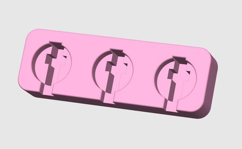 May include: A light pink, rectangular mold with three circular cavities. Each cavity has a stylized, geometric design. The mold is designed for creating multiple identical objects.