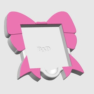 May include: A pink and white bow-shaped picture frame. The frame has a square opening in the center and the letters "BSD" are visible. The bow design features a layered effect with pink and white accents, creating a three-dimensional look.