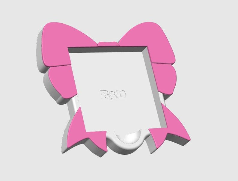 May include: A pink and white bow-shaped picture frame. The frame has a square opening in the center and the letters "BSD" are visible. The bow design features a layered effect with pink and white accents, creating a three-dimensional look.