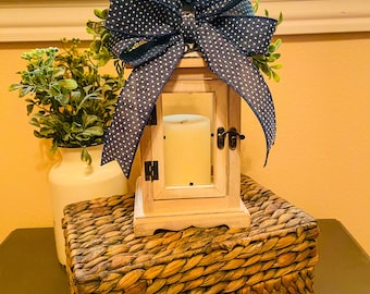 Candelabro estilo farol de granja, lazo azul y vegetación, madera encalada