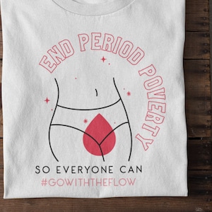 Könnte beinhalten: Weißes T-Shirt mit einem pinkfarbenen und schwarzen Grafikdesign. Die Grafik zeigt einen stilisierten weiblichen Körper mit einem roten Blutstropfen und dem Text "End Period Poverty So Everyone Can #GoWithTheFlow".