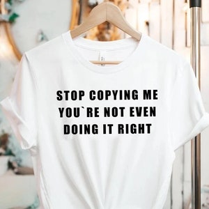 Peut inclure: T-shirt blanc avec un texte noir qui dit "STOP COPYING ME YOU'RE NOT EVEN DOING IT RIGHT"