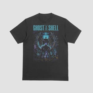 Könnte beinhalten: Ein schwarzes Kurzarm-T-Shirt mit einem Grafikdruck und dem Text GHOST IN THE SHELL 1995. Das Design zeigt eine zentrale Figur, umgeben von komplexen blauen und violetten kybernetischen Mustern, geometrischen Formen und japanischen Schriftzeichen.