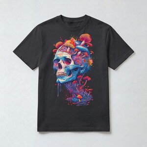 Op de afbeelding: Een zwart t-shirt met korte mouwen en een levendige grafische print van een menselijke schedel in blauwe en paarse tinten, met diverse kleurrijke paddenstoelen die uit de bovenkant en zijkanten groeien, en verfachtige druppels onderaan.