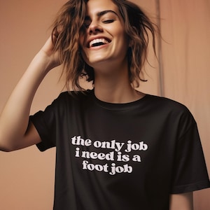 Puede incluir: Camiseta negra con texto blanco que dice "the only job i need is a foot job".