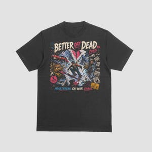 May include: A black short-sleeved t-shirt featuring a graphic print with the text "BETTER OFF DEAD 1985" at the top and "HEARTBREAK. SKI WAR. CHAOS." at the bottom. The illustration includes a skier, a bicycle, a car, and a monster figure.