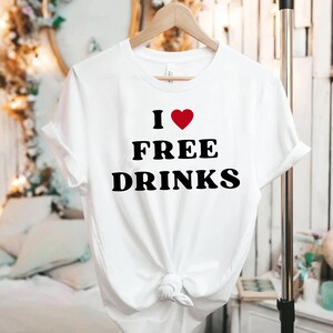May include: White t-shirt with a black graphic that says "I ♥ FREE DRINKS".