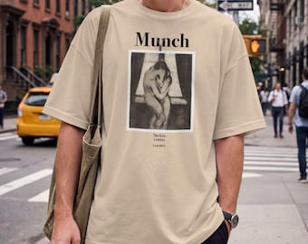 May include: A beige short-sleeved t-shirt featuring a black and white graphic print of Edvard Munch's The Kiss (1895). The text Munch is printed above the artwork, with The Kiss (1895) and Taschen printed below the square image on the chest.