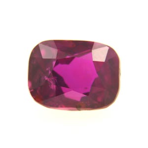 Peut inclure: Une pierre précieuse taillée en coussin, d'une couleur magenta intense. Les facettes de la gemme captent la lumière, créant un effet scintillant. La pierre est présentée sur un fond blanc uni, soulignant sa couleur et sa clarté.