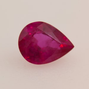 Puede incluir: Una piedra preciosa de rubí en forma de pera con un color rojo intenso.