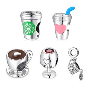Könnte beinhalten: Satz von sechs silbernen Charms mit verschiedenen Designs. Die Charms beinhalten eine Kaffeetasse mit den Worten "Love Coffee", ein Weinglas mit dem Wort "Wine", eine Kaffeetasse mit einem Herzen, ein Glas mit einem rosa Herzen und zwei Kaffeetassen mit den Worten "Coffee" und "Love".