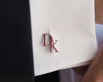 Puede incluir: Gemelos de plata con las iniciales "DK" en una fuente moderna.
