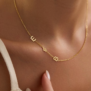 Può includere: Una delicata collana color oro con le lettere "E" e "B", con un simbolo di nota musicale tra di esse. La collana è indossata intorno al collo, con la catena a contatto con la pelle. La collana è un gioiello semplice ed elegante.