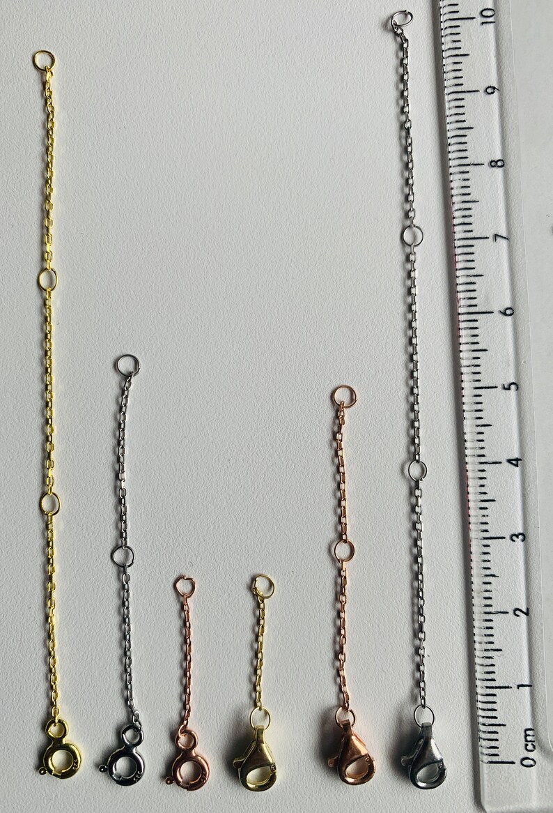 Puede incluir: Cinco extensores de cadena diferentes en oro, plata y oro rosa. Las cadenas miden aproximadamente 10 cm de largo y tienen un cierre de langosta en el extremo.