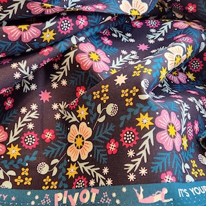 Puede incluir: Una tela azul oscuro con un patrón floral con flores rosas, amarillas y blancas. La tela tiene un borde turquesa con el texto "Pivot" y "It's Your Time!" impreso en ella.
