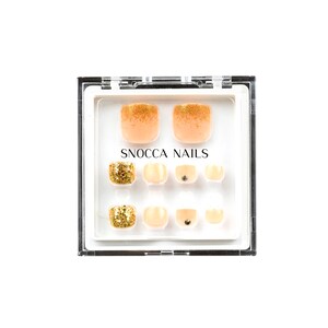 Puede incluir: Una caja de plástico transparente con un interior blanco que contiene un juego de 10 uñas postizas para los dedos de los pies. Las uñas son de color melocotón claro con purpurina dorada en las puntas. La caja tiene el texto "SNOCCA NAILS" impreso en la parte delantera.