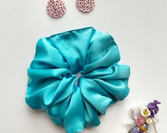 May include: A turquoise blue satin scrunchie with two pink floral earrings.