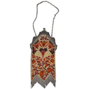 May include: A vintage silver mesh purse with a chain strap. The purse is decorated with a floral pattern in shades of orange, pink, and yellow.