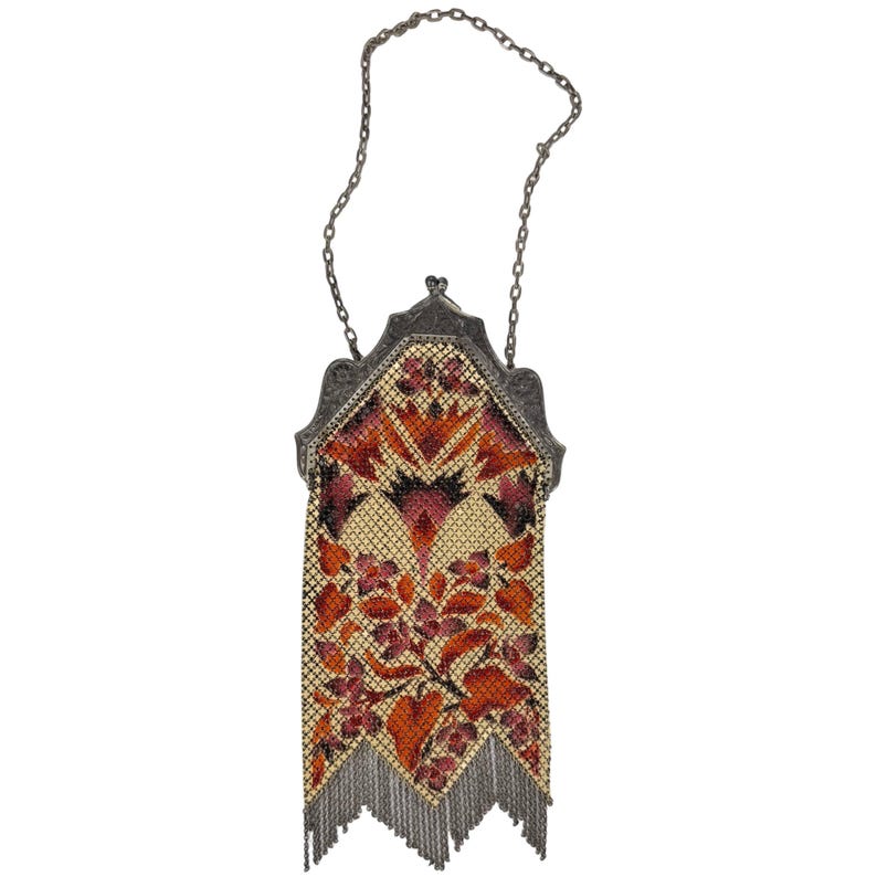 May include: A vintage silver mesh purse with a chain strap. The purse is decorated with a floral pattern in shades of orange, pink, and yellow.