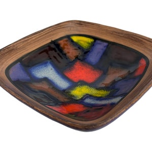 May include: Square ceramic dish with a brown rim and a colourful geometric design in shades of blue, red, yellow, and brown.