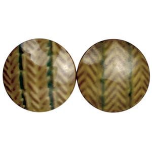 May include: Two round ceramic tiles with a brown and green chevron pattern.