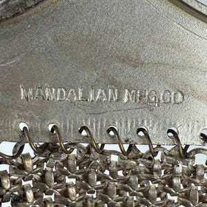 May include: A silver chain purse with a metal clasp and the inscription "MANDALIAN MFG. CO."