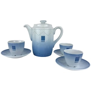 May include: A porcelain tea set comprising a teapot and three teacups with saucers. The set has a gradient blue colour scheme with a white top and a decorative pattern. Each cup and the teapot feature a vertical stripe design.
