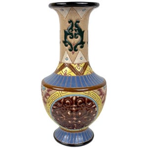 May include: A decorative ceramic vase with a black rim and base. The vase features a tan background with geometric patterns, blue and yellow bands, and a brown, ornate design. The vase is approximately 30 cm tall.