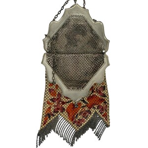 May include: A silver mesh purse with a floral design and fringe. The purse has a hinged top and a chain strap.