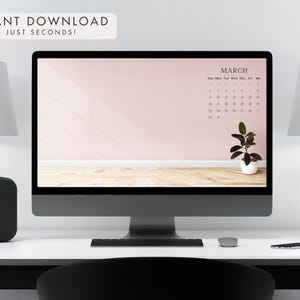 May include: A desktop computer displays a March calendar on a pink background with a small potted plant. The text "INSTANT DOWNLOAD APPLY IN JUST SECONDS!" is at the top. The computer sits on a white desk with lamps and a speaker.