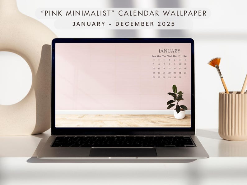 May include: A laptop displays a pink minimalist calendar wallpaper for January-December 2025. The screen shows a calendar with a small potted plant. A brush and pencils sit in a beige holder. The text "PINK MINIMALIST" and "CALENDAR WALLPAPER" is at the top.
