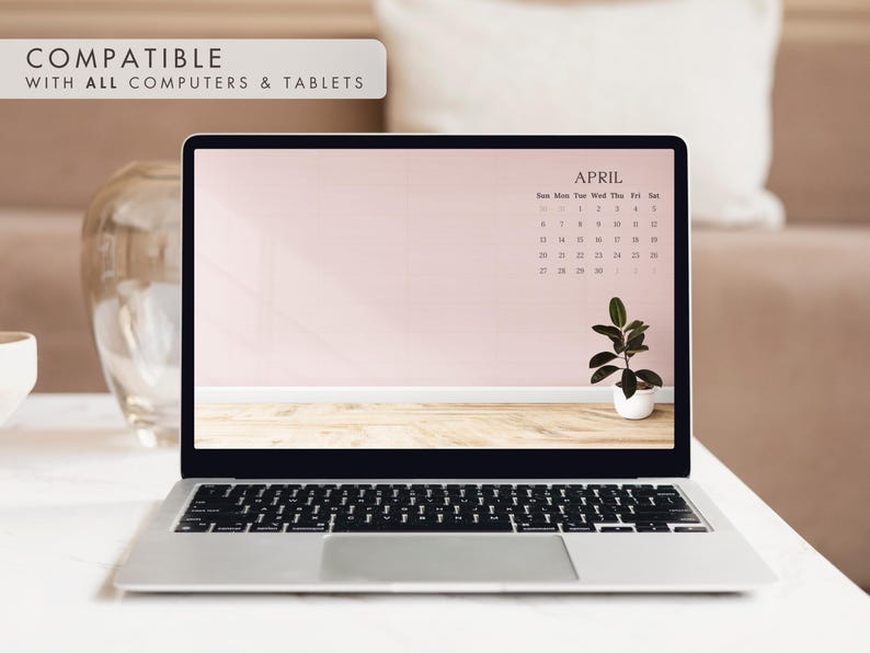 May include: A laptop displays an April calendar on its screen, set against a light pink wall and wooden floor. A small potted plant sits on the screen. The text "COMPATIBLE WITH ALL COMPUTERS & TABLETS" is at the top.