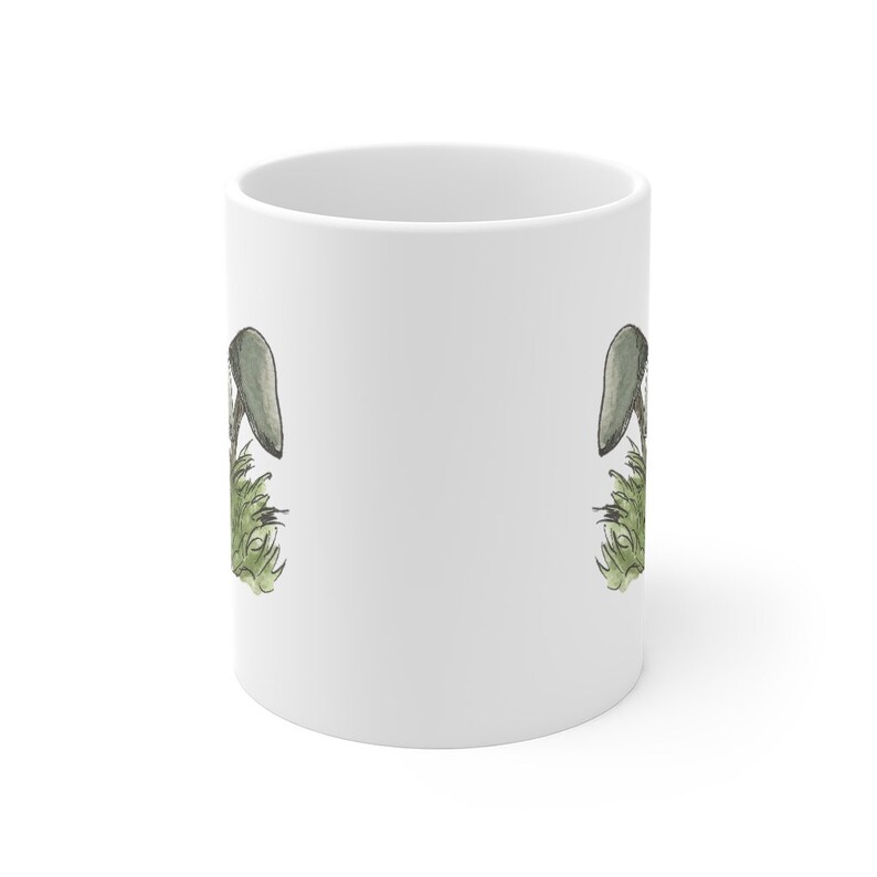 Pode incluir: Caneca de cer&acirc;mica branca com uma ilustra&ccedil;&atilde;o de cogumelo verde e cinza de cada lado.