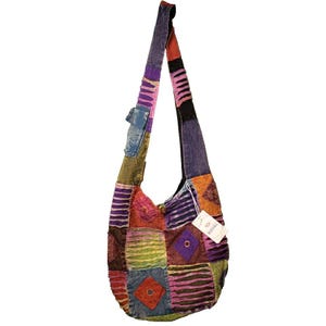 May include: A patchwork hobo bag featuring a long shoulder strap and a variety of colorful fabric squares in shades of purple, orange, green, blue, and red. The bag includes a small exterior pocket and a white tag with the text ROYAL.