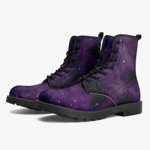 May include: A pair of ankle-high lace-up boots featuring a purple and black galaxy print with scattered white stars. The boots have black laces, black metal eyelets, black trim along the edges, and a solid black rubber sole.