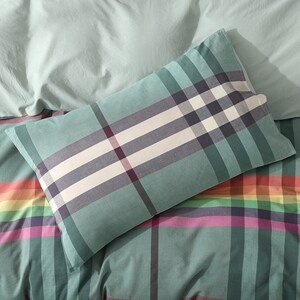 May include: A green and white plaid pillow with a rainbow plaid pattern on the bottom.