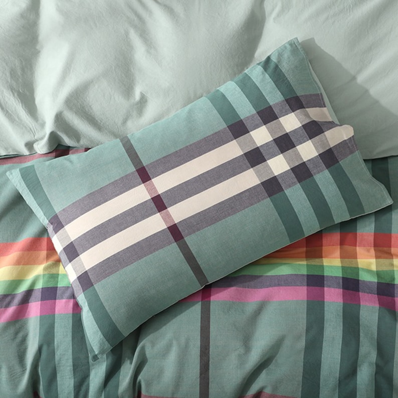 May include: A green and white plaid pillow with a rainbow plaid pattern on the bottom.