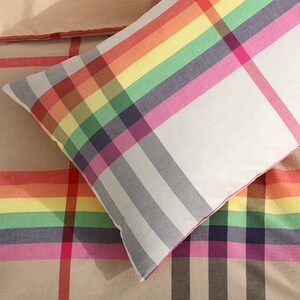 May include: A white pillowcase with a rainbow plaid pattern. The pillowcase is made of soft cotton and is perfect for adding a touch of color to your bedroom.