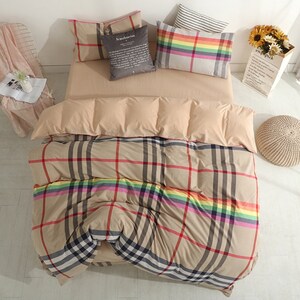 May include: Beige and brown plaid bedding with a rainbow stripe. The bedding is on a bed with two pillows, one with a rainbow stripe and one with a gray pillow with the word "Scandinavian" printed on it.