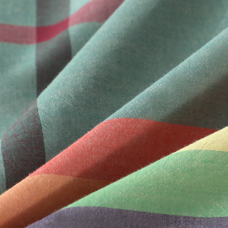 May include: Close-up of a fabric with a striped pattern in shades of green, red, orange, and purple. The fabric is folded and the stripes are visible in the folds.