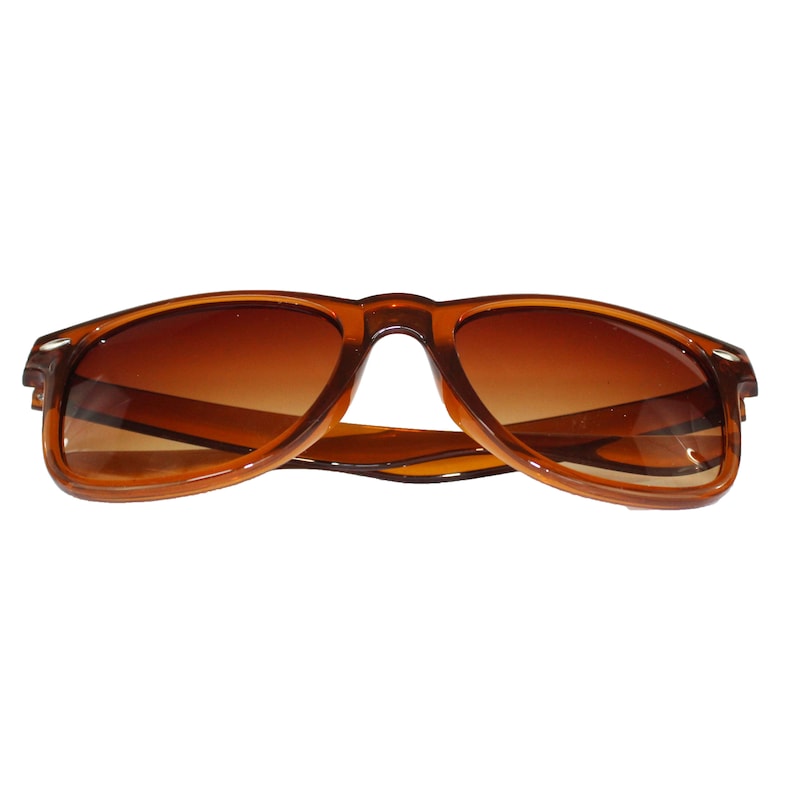 May include: Brown plastic sunglasses with brown lenses. The sunglasses are in focus and the background is blurred.